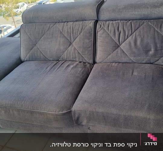 ספה אפורה עם ריפוד מרופד, נראית נקייה ומסודרת.
